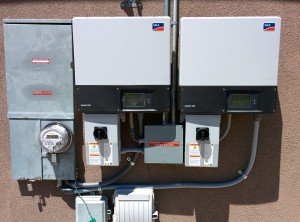 A pair of SMA Sunny Boy string inverters next to the net meter (left).